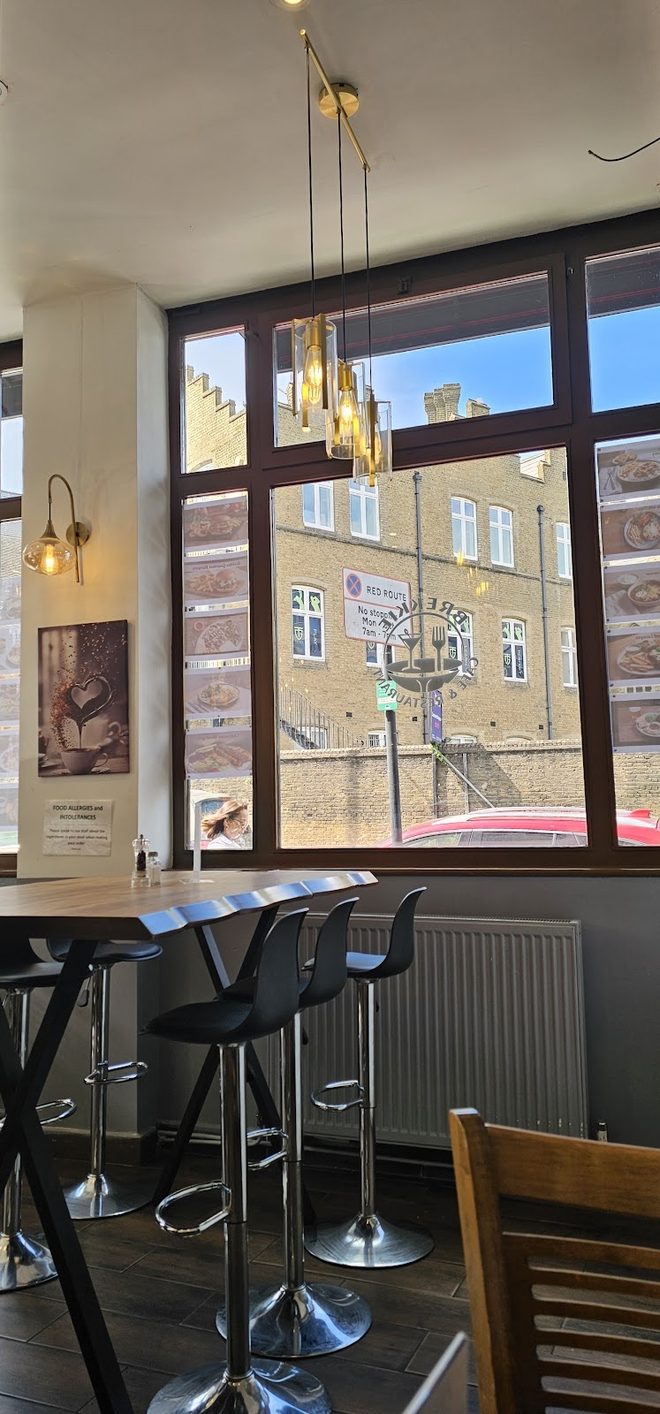 A window table with coffees, water and a large plate of nachos