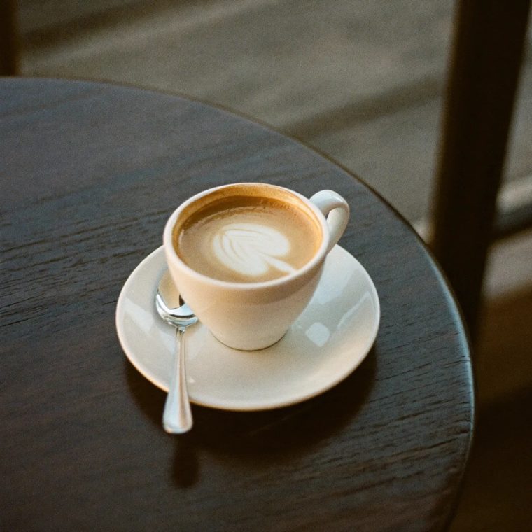 A flat white coffee on a dark wooden table