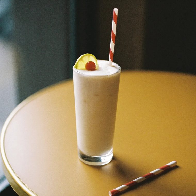 A milkshake in a tall glass on a yellow table